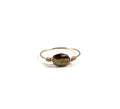 Cette bague met en valeur une petite pierre fine ovale facettée, dont les reflets naturels apportent lumière et délicatesse au bijou.

La pierre est délicatement maintenue par un fil en gold filled 14 carats, formant un design fin et épuré qui souligne la beauté de la pierre.