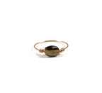 Cette bague met en valeur une petite pierre fine ovale facettée, dont les reflets naturels apportent lumière et délicatesse au bijou.

La pierre est délicatement maintenue par un fil en gold filled 14 carats, formant un design fin et épuré qui souligne la beauté de la pierre.